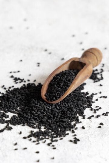 Close-up of Kalonji seeds, also known as nigella seeds, showing their black, teardrop shape and matte texture.