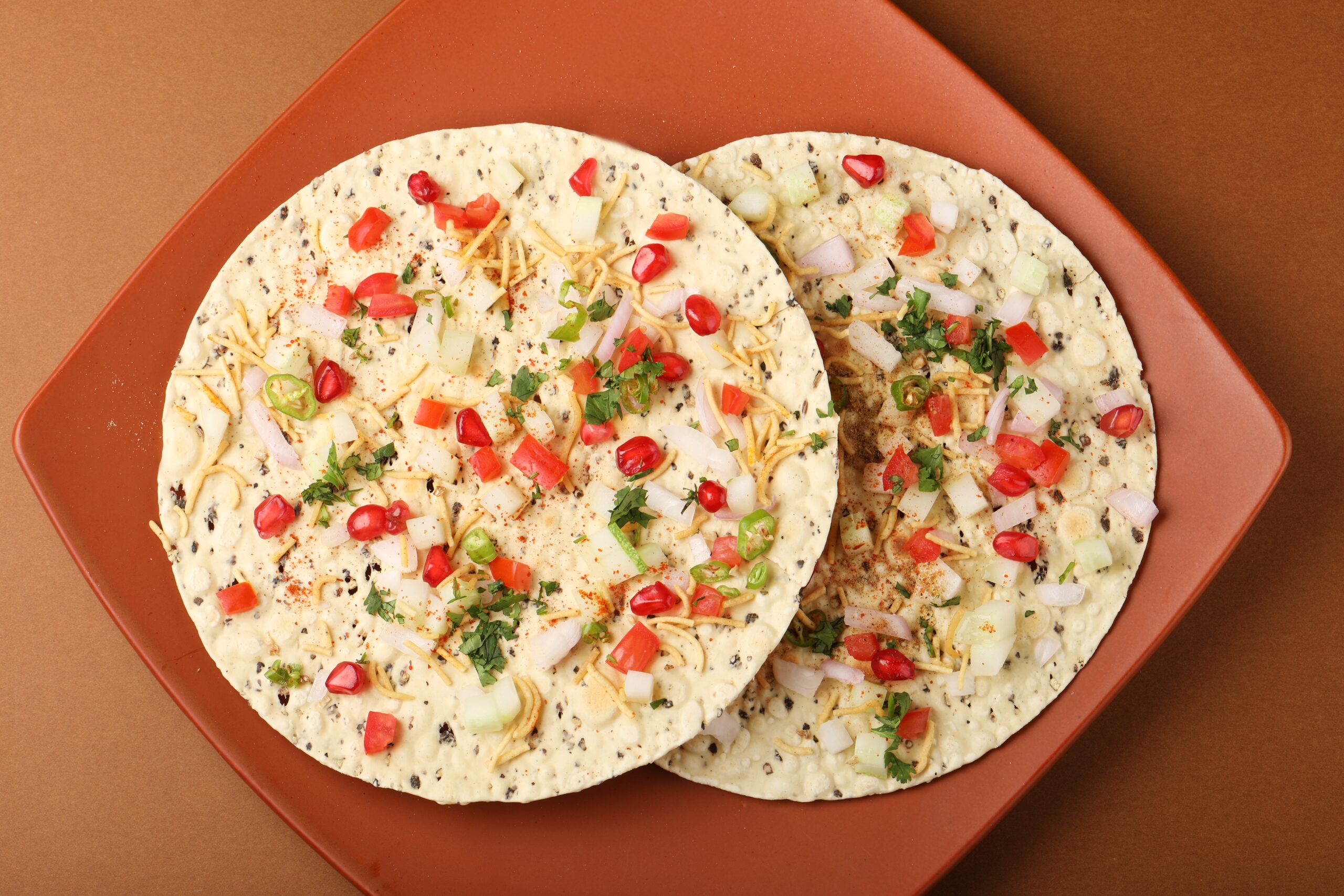 Masala papad topped with fresh onions, tomatoes and spices.