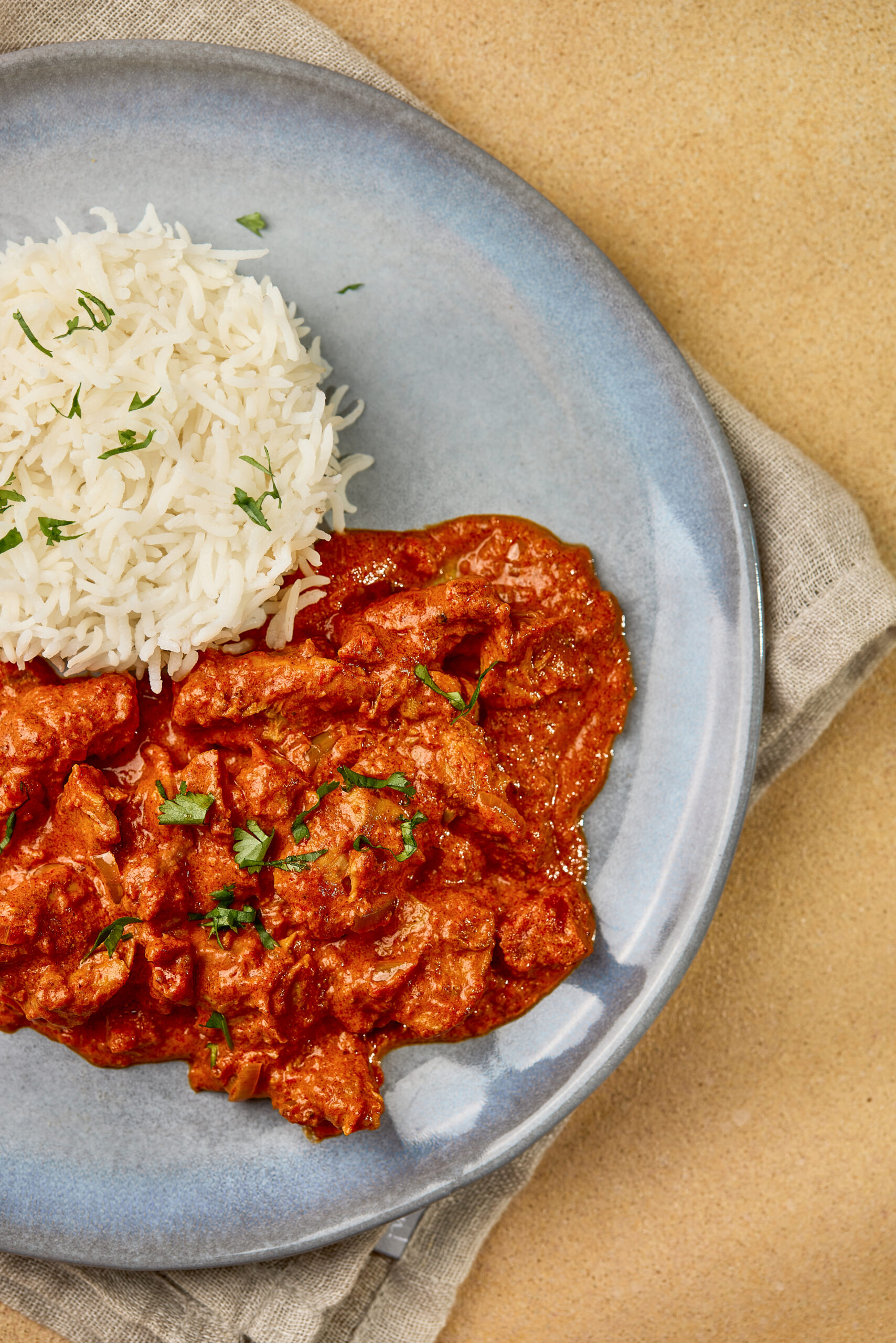 Close-up of Butter Chicken showing tender chicken pieces in rich, orange tomato-cream gravy.