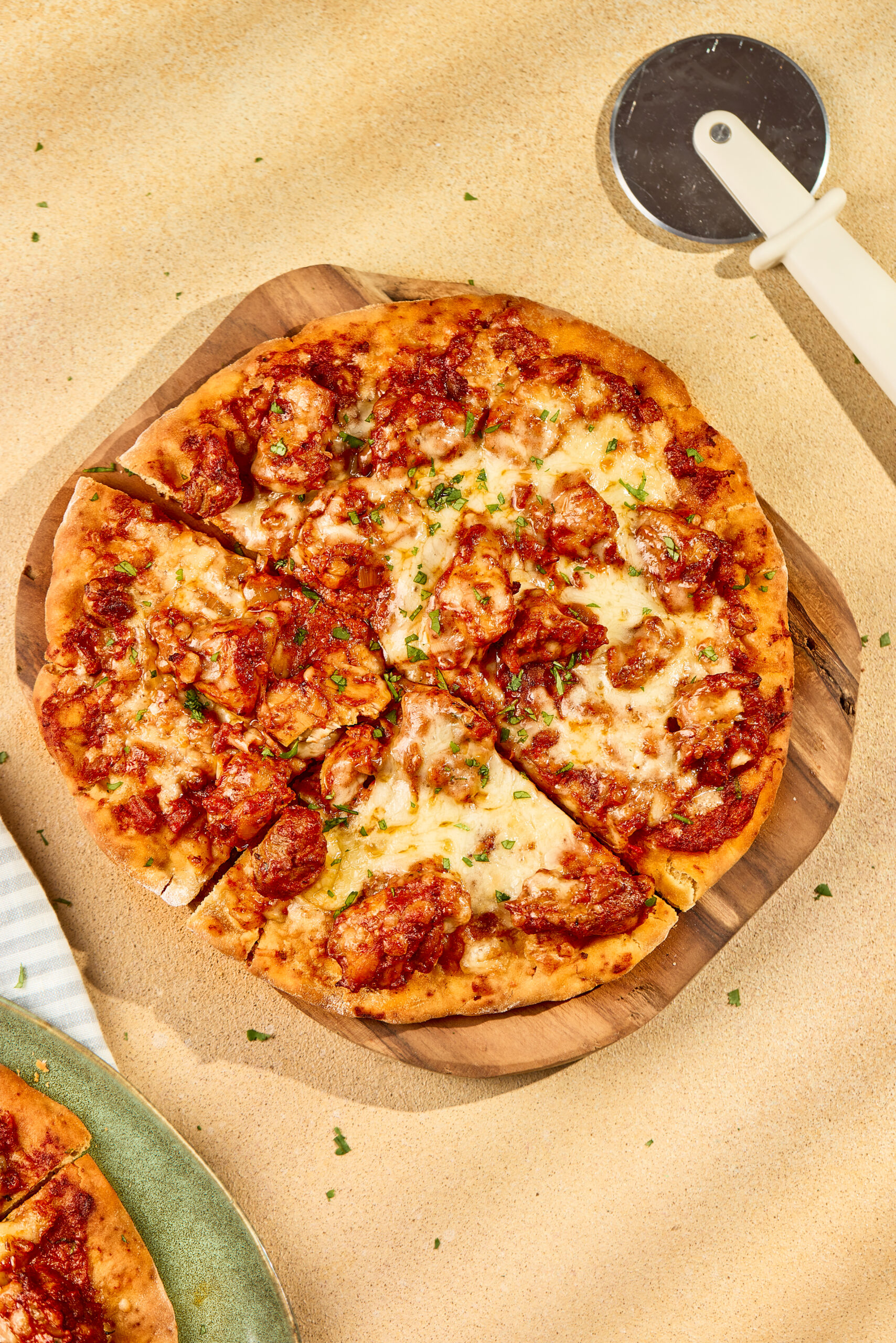 Butter Chicken Pizza topped with mozzarella, cheddar, onions, and cilantro on a golden crust.