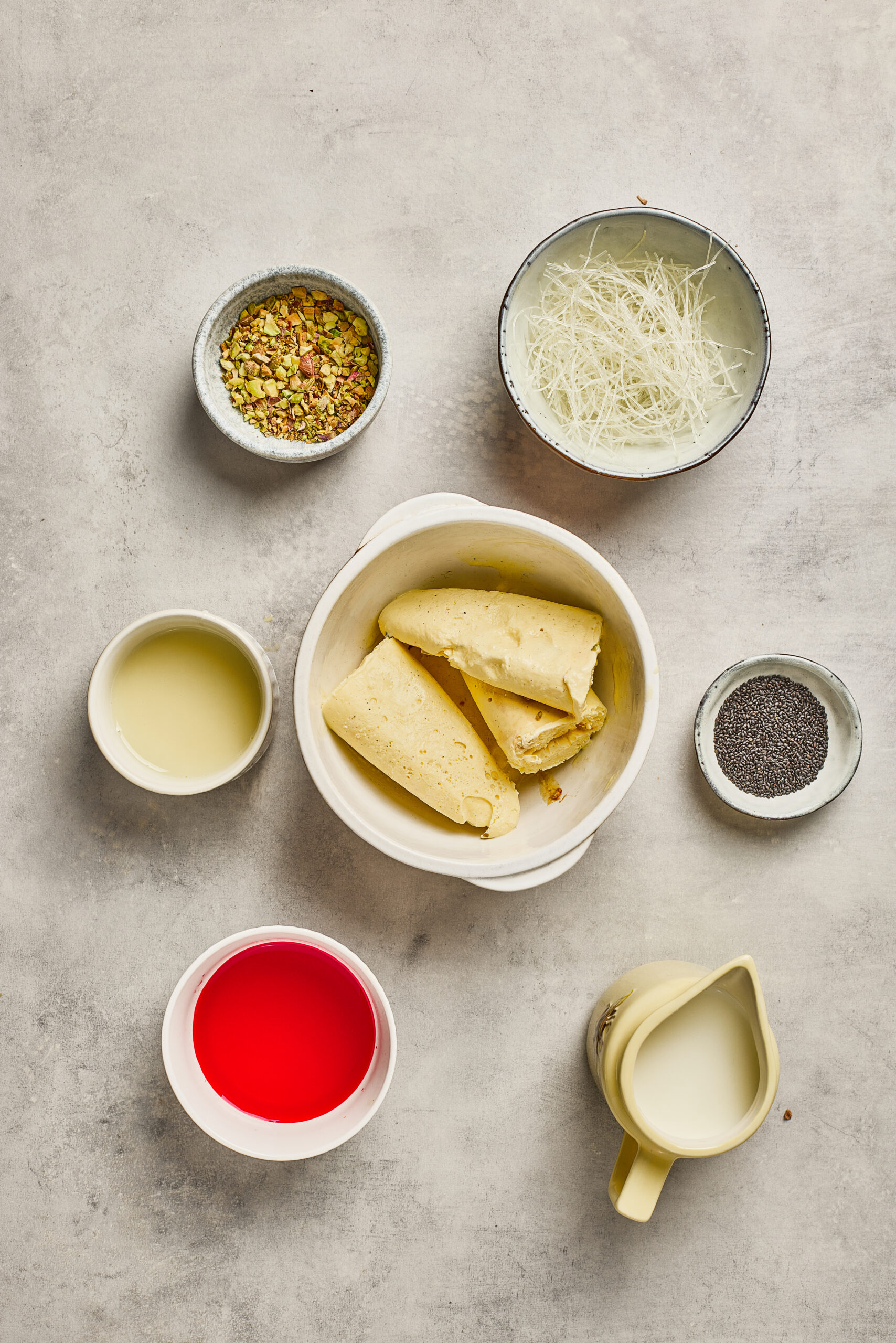 Ingredients for Falooda including rose syrup, basil seeds, vermicelli, milk, ice cream, and nuts