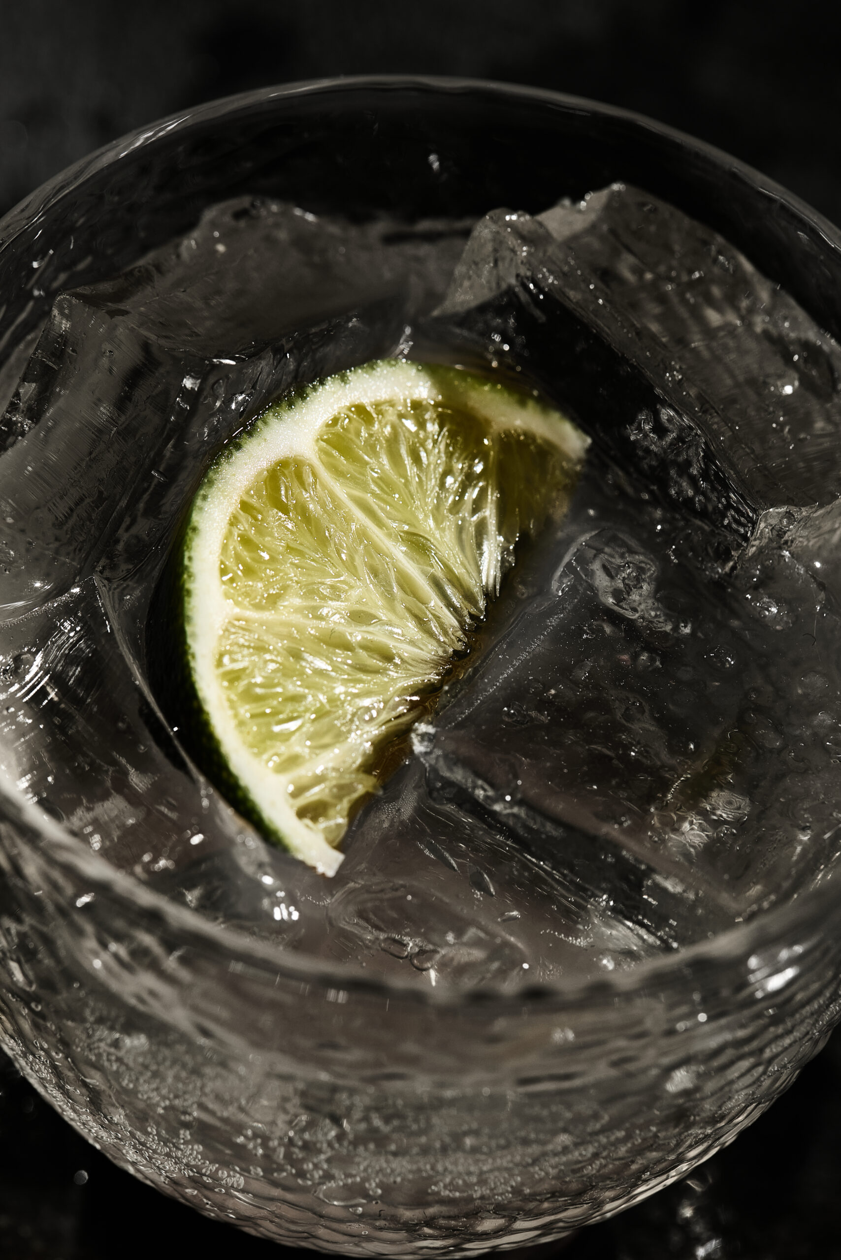 Close-up of lime soda showing fizzy bubbles, ice cubes, and fresh lime slices in the glass