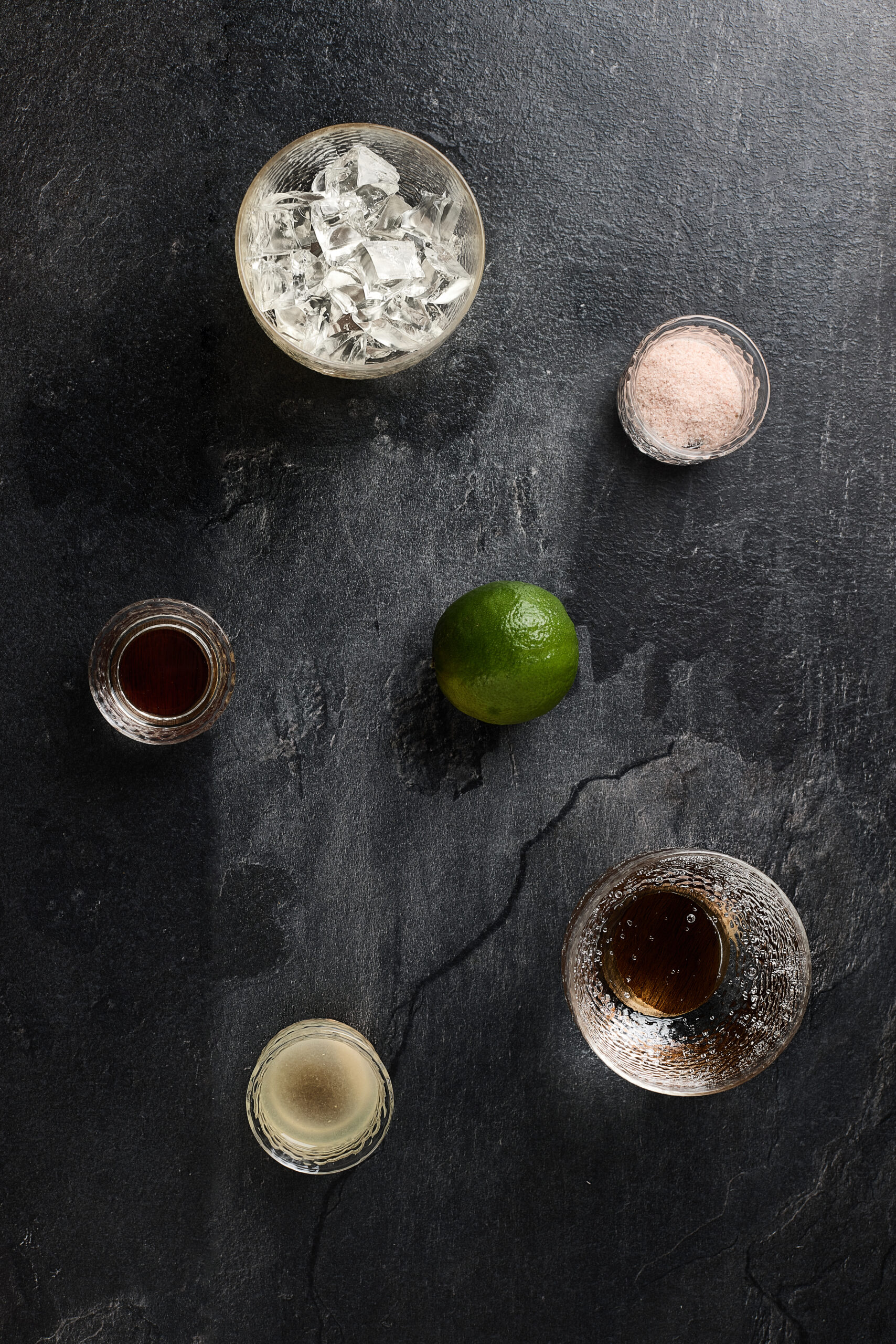 Ingredients for lime soda including fresh limes, soda water, sugar, salt, black salt on a table
