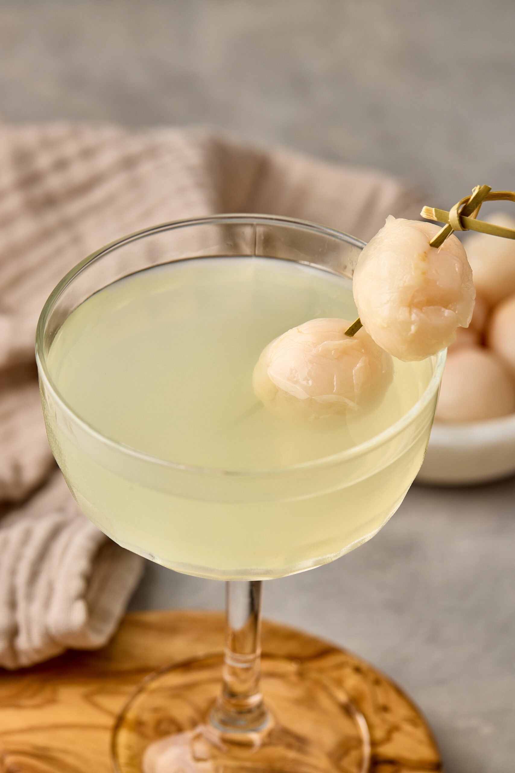 Close-up of Lychee Martini showing clear, pale drink with lychee garnish.