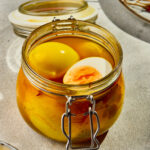 Pickled eggs in a glass jar with vinegar brine, spices.