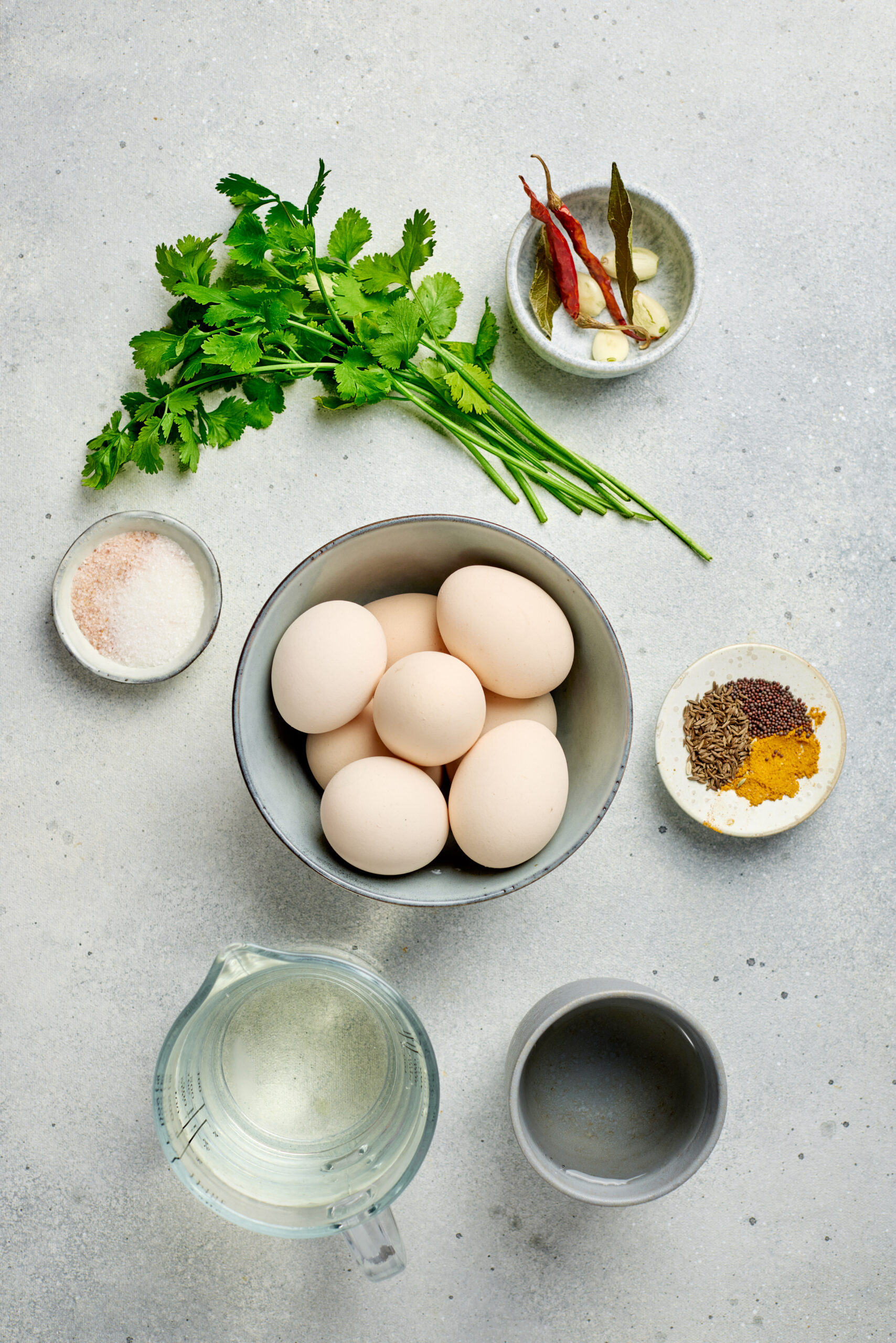 Hard-boiled eggs, vinegar, spices arranged on a kitchen counter for pickled eggs