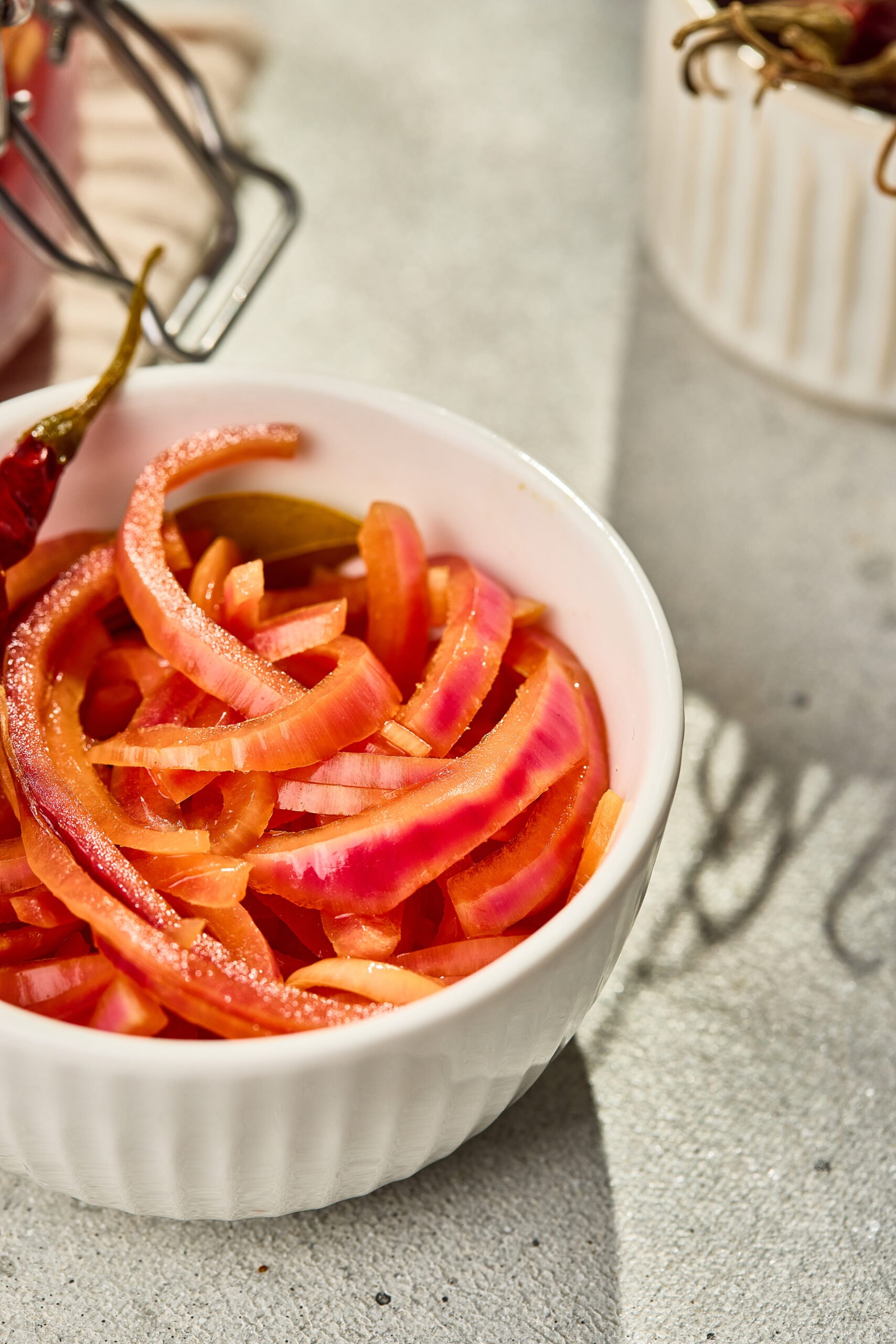Close-up of vibrant pink pickled red onions showing glossy texture and curled slices