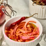Bright pickled red onions in a white bowl, tangy vinegar brine onions served as a condiment for tacos, salads, and curries