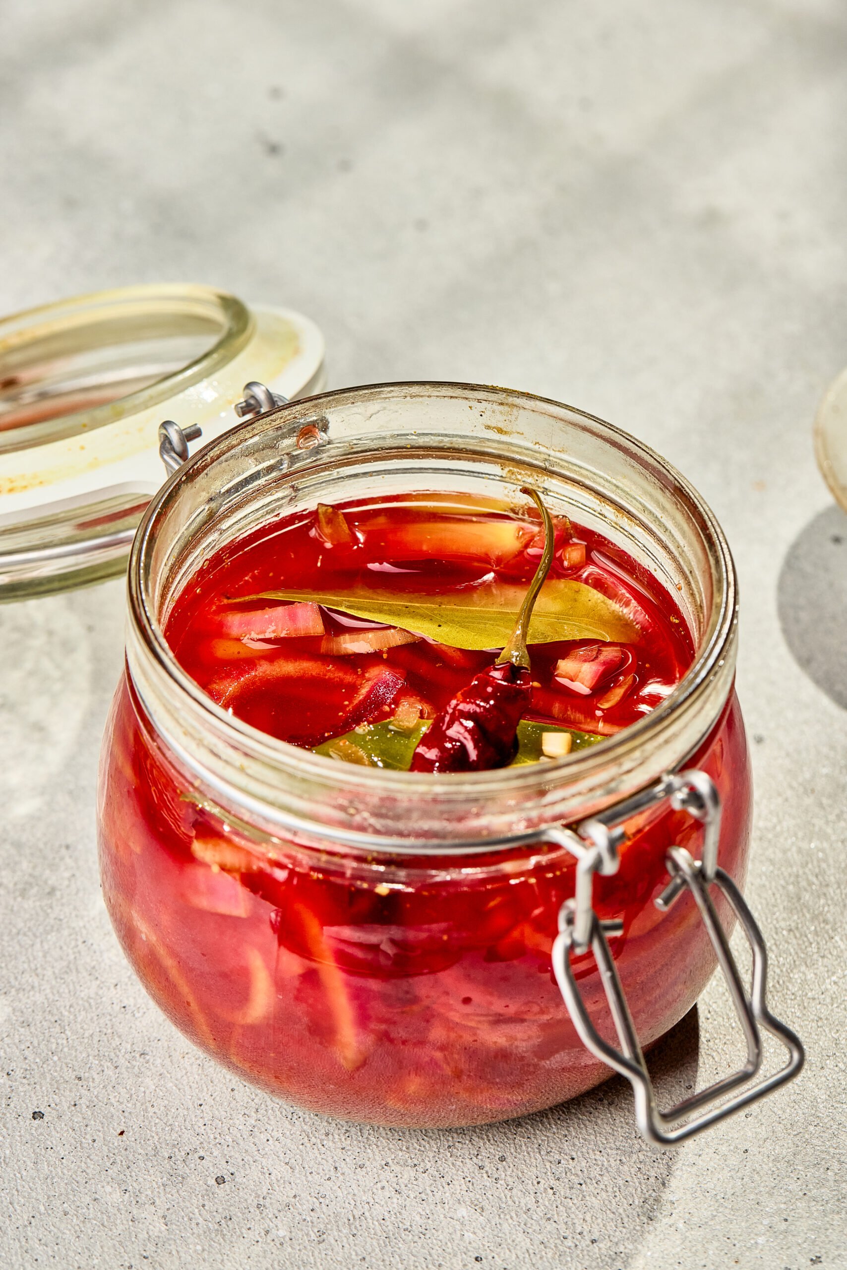 Pickled red onions in a glass jar with vinegar brine and mustard seeds, ready to serve as a tangy condiment