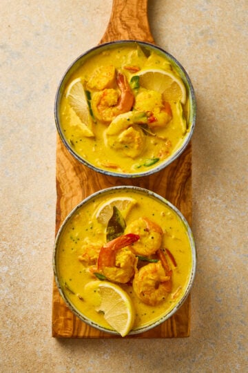 Prawn Moilee served in a bowl with creamy coconut curry, garnished with curry leaves and green chilies