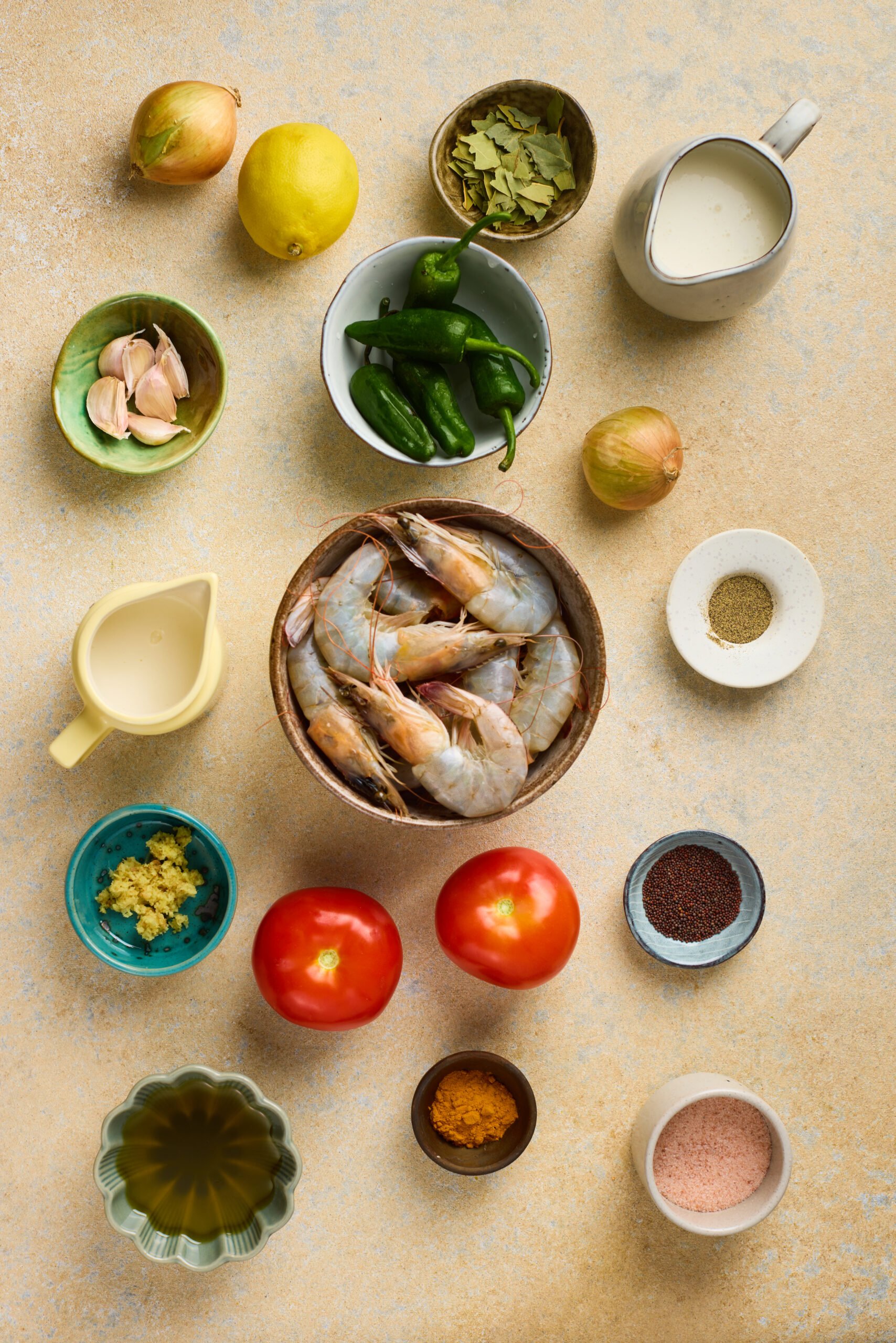 Ingredients for Prawn Moilee including prawns, coconut milk, curry leaves, ginger, green chilies, onions, and spices arranged on a table