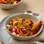 Samosa Chaat served in a bowl with onions and pomegranate garnish.