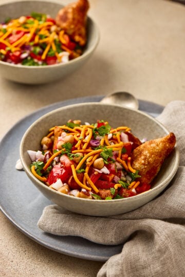 Samosa Chaat served in a bowl with onions and pomegranate garnish.