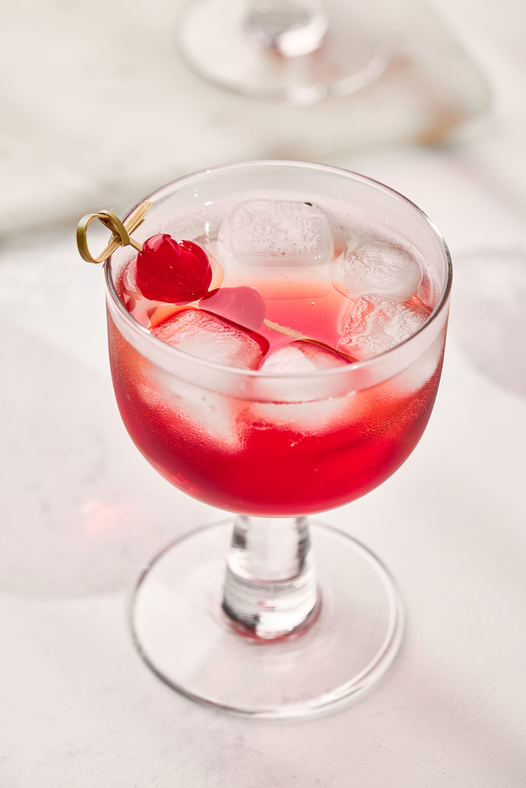Close-up of Shirley Temple Drink showing fizzy bubbles, bright red grenadine, and cherry garnish.