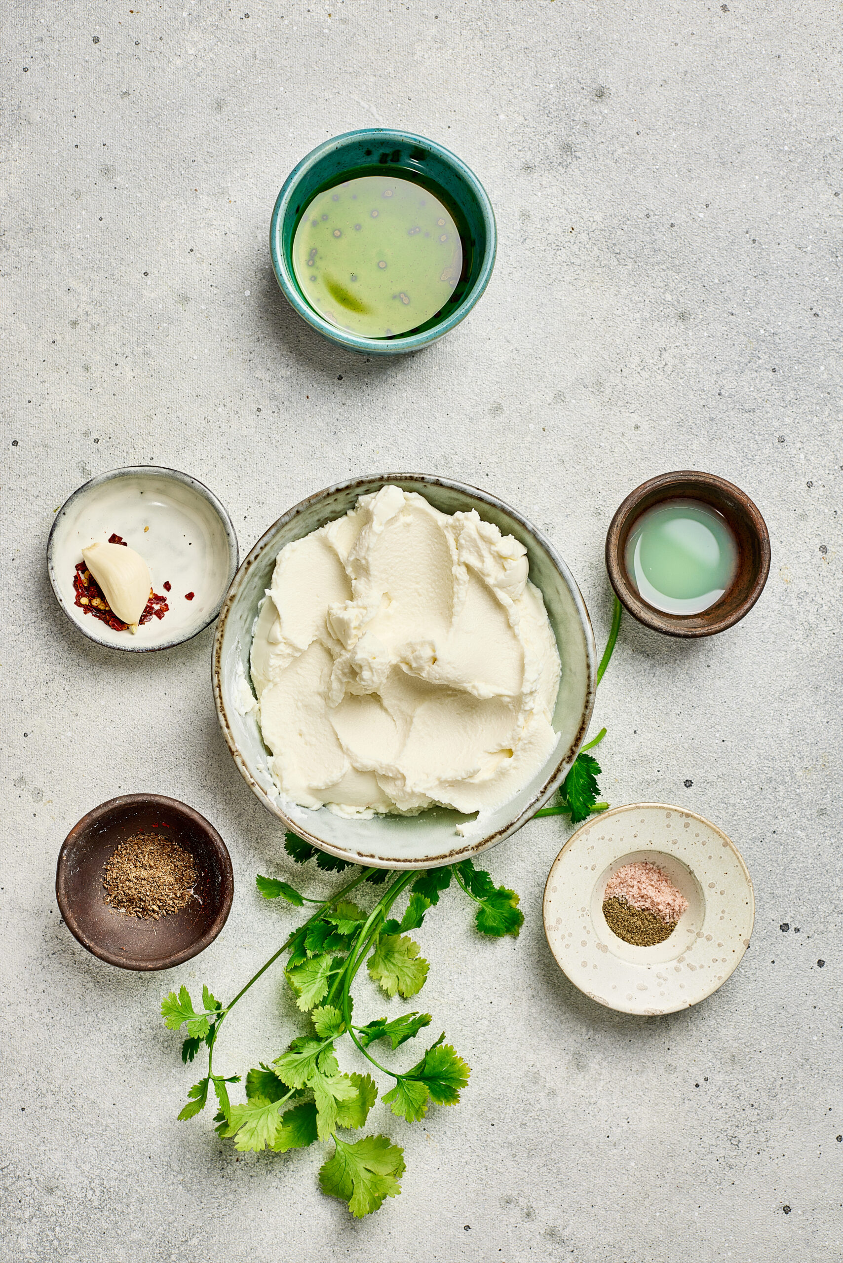 Ingredients for Whipped Ricotta including ricotta cheese, olive oil, lemon, salt, and pepper arranged on a counter.