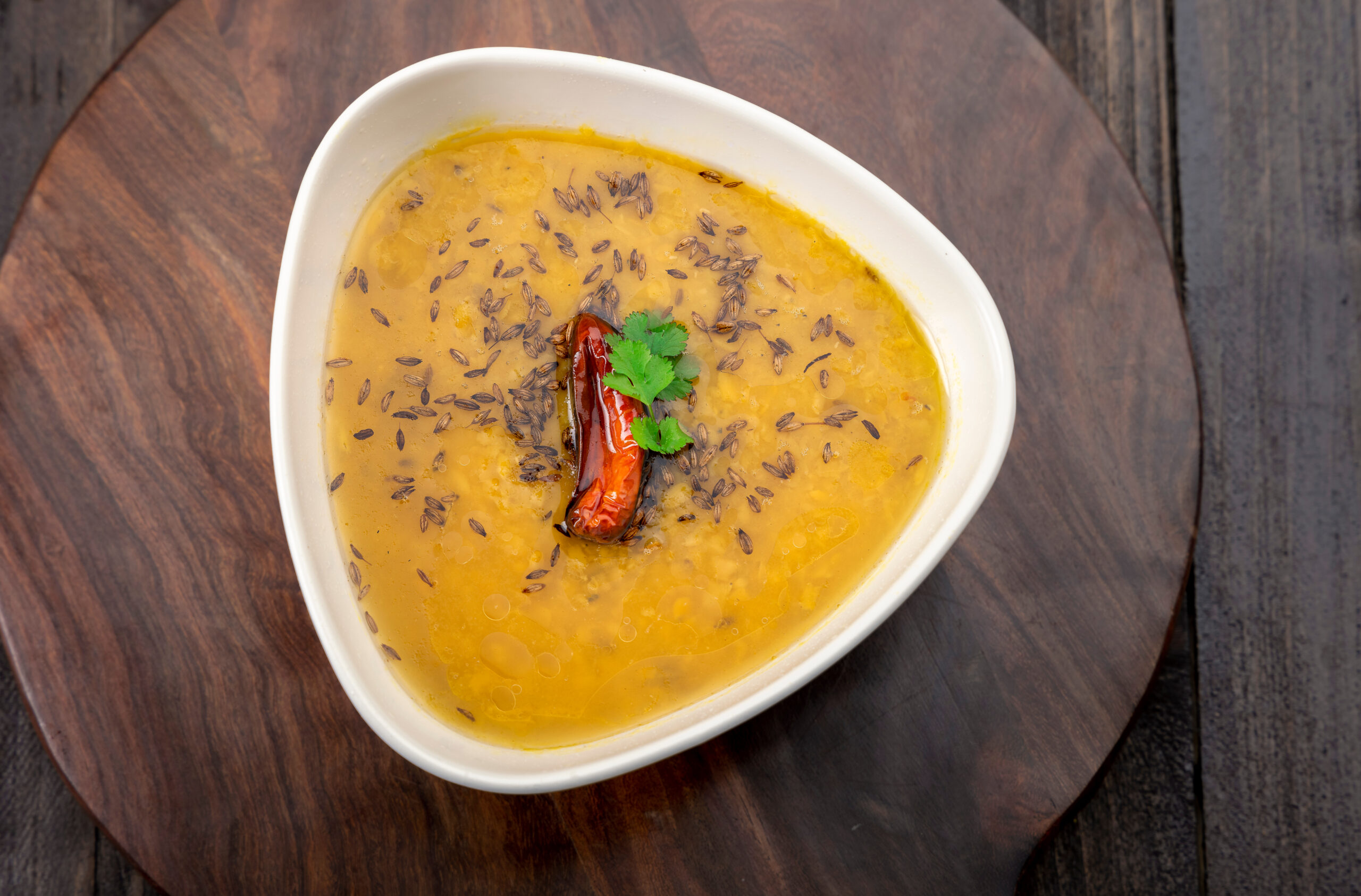 Cooked moong dal in a bowl; creamy yellow lentil dish seasoned with Indian spices, known for its light texture and comforting taste.