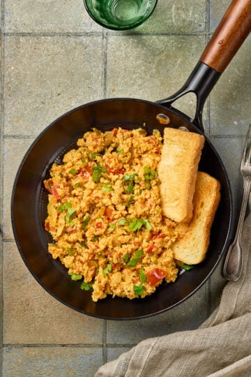 Egg Bhurji served in a bowl, garnished with fresh coriander and paired with buttered pav bread.