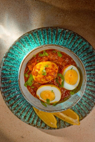 Egg Pulusu served in a clay bowl with boiled eggs in tangy tamarind gravy, garnished with coriander.
