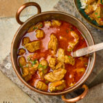Mutton Curry served in a bowl with rich spiced gravy, garnished with fresh coriander leaves.