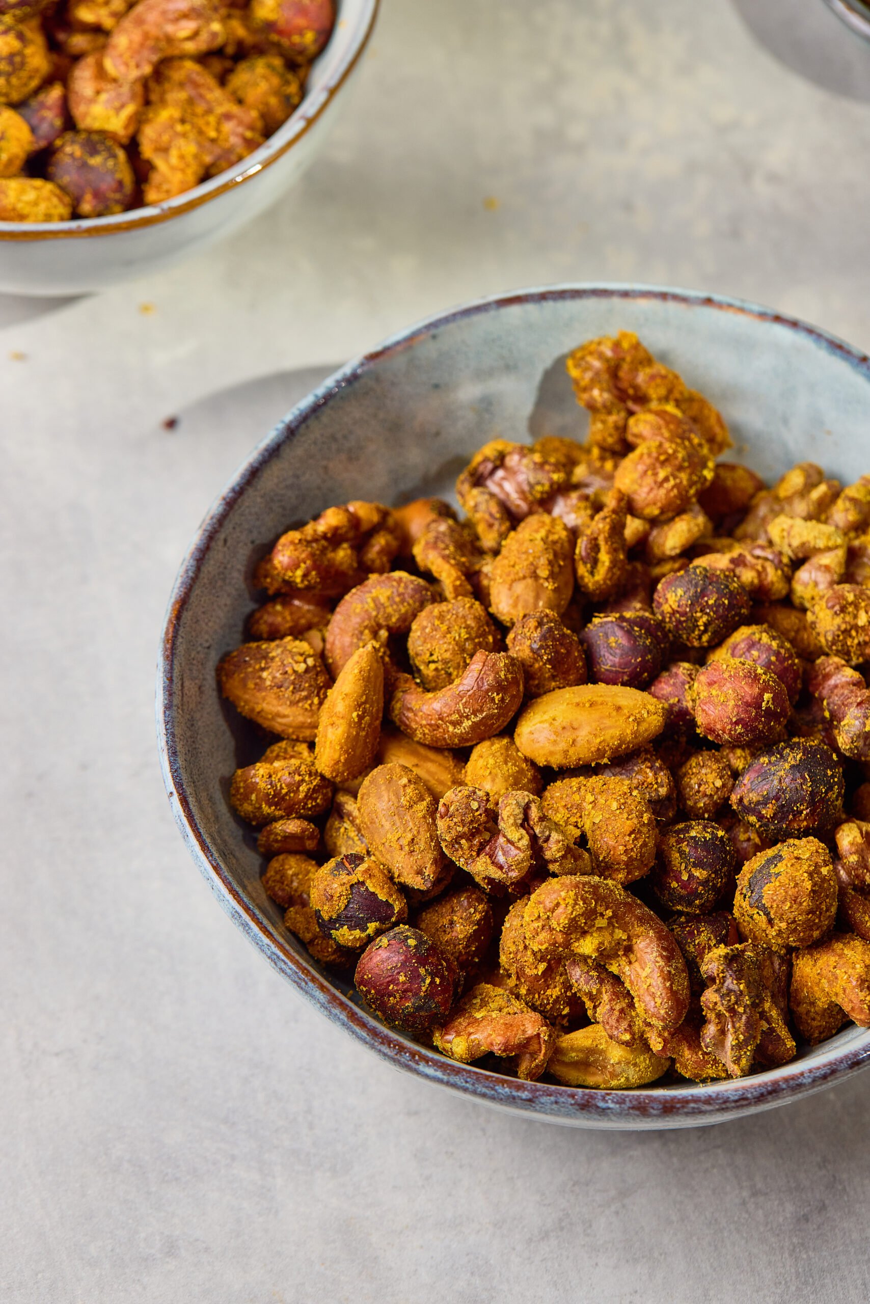 Close-up of Spiced Nuts showing glossy, roasted coating with visible chili and spice flecks.