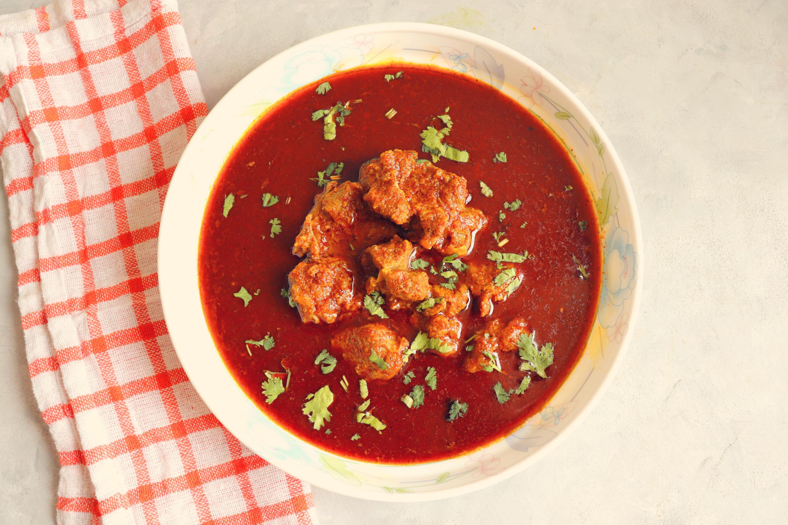 Tambda Rassa; traditional Kolhapuri red curry made with a rich blend of roasted spices and meat, known for its deep color and bold character.