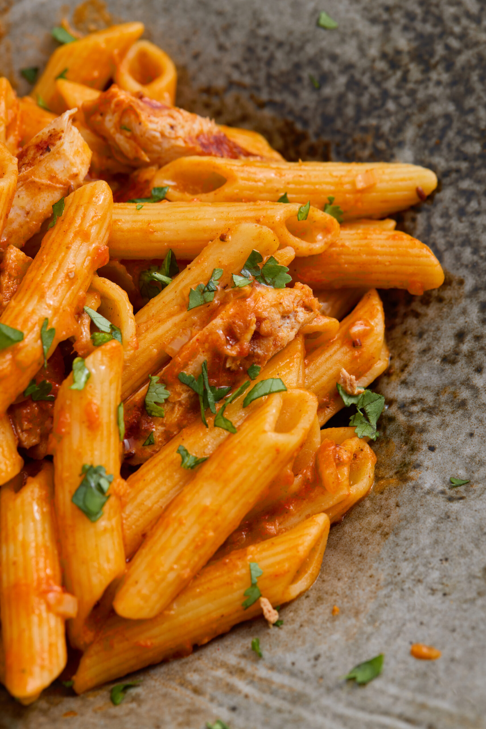Close-up of creamy butter chicken pasta with chicken pieces and sauce.