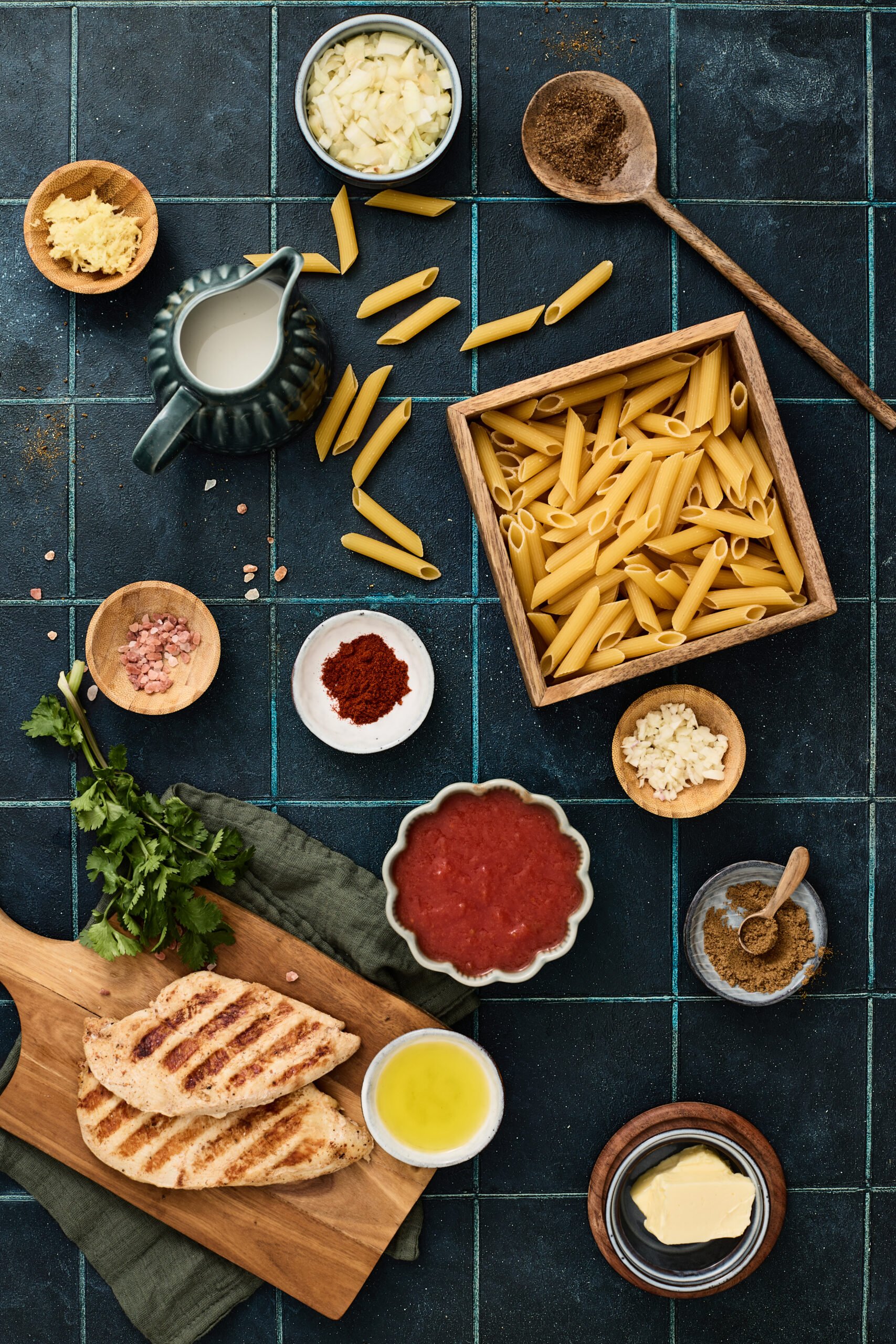 Ingredients for butter chicken pasta arranged on a counter.