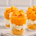Mango Cheesecake Jars layered with biscuit base, creamy filling, and fresh mango topping.