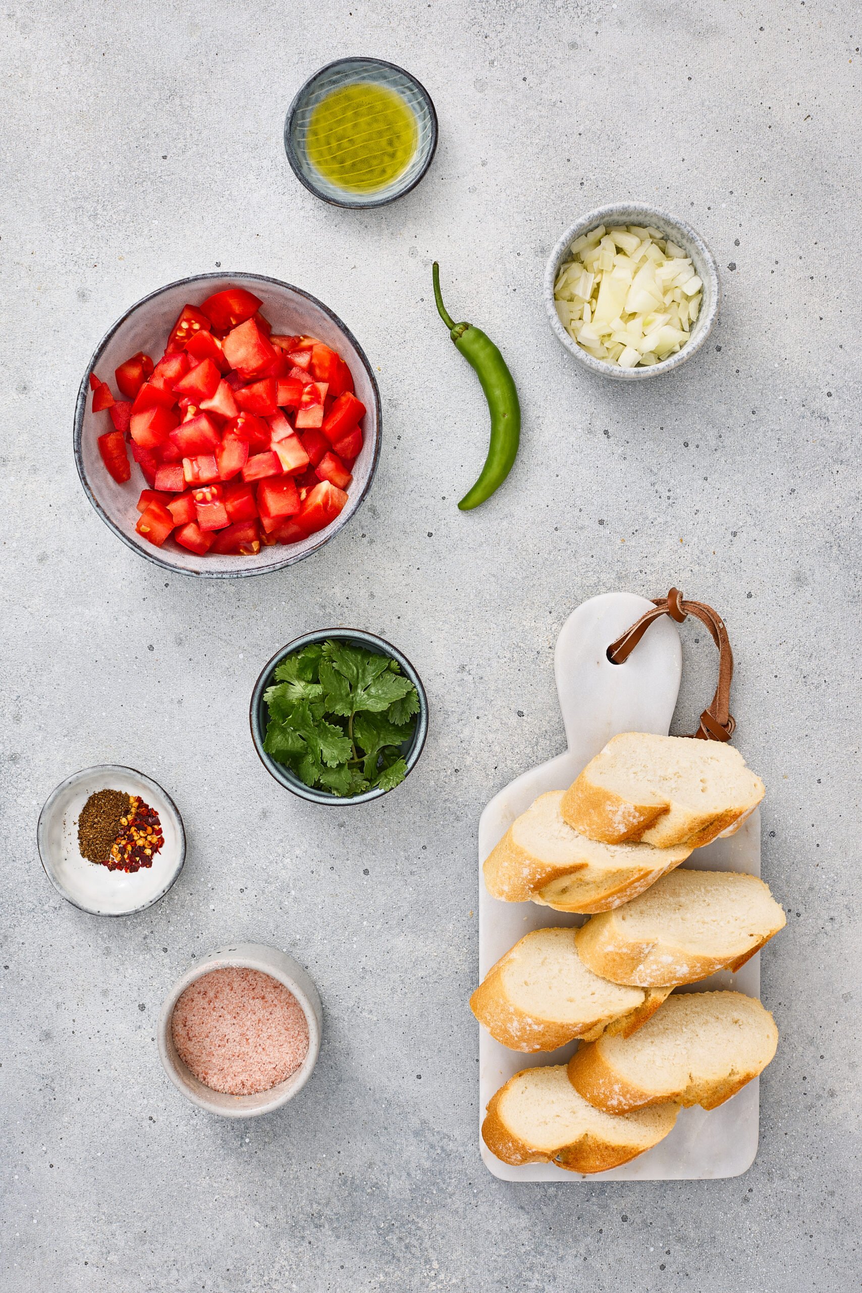 Ingredients for Masala Bruschetta including tomatoes, onions, spices, herbs, and bread.