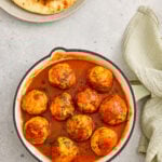 Juicy meatballs in tomato curry sauce garnished with fresh coriander.