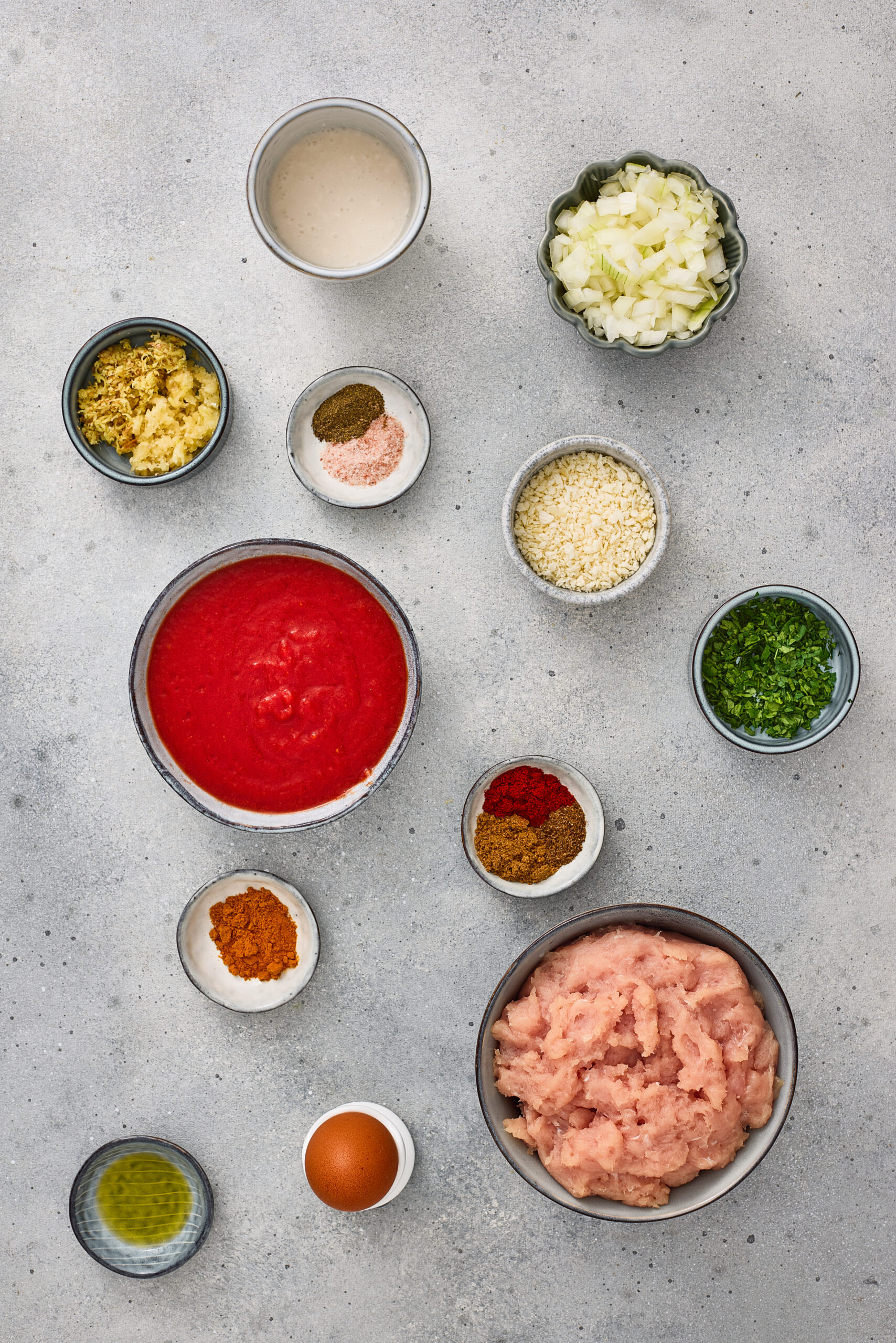 Ingredients for Indian-style masala meatballs including minced meat, tomatoes, onions, spices, and herbs.