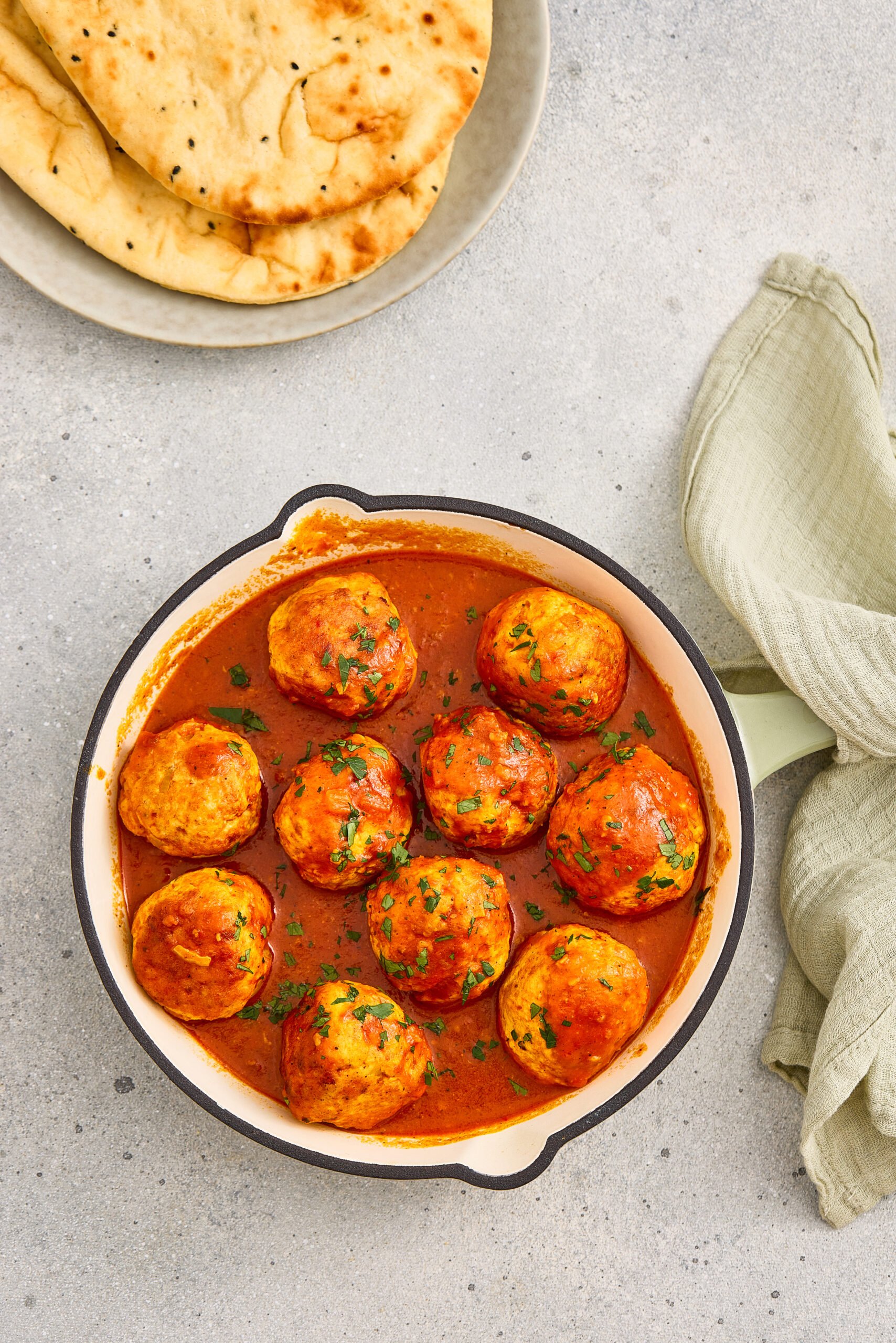 Juicy meatballs in tomato curry sauce garnished with fresh coriander.