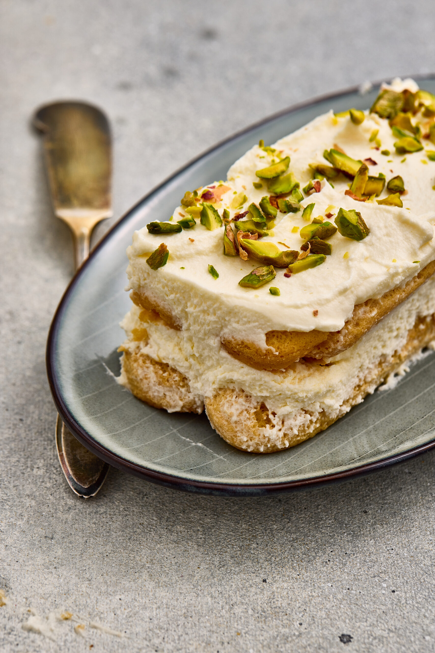 Pistachio rose tiramisu sliced and served on a plate.