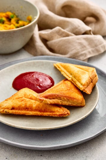 Crispy Samosa Toasties cut into triangles and served on a plate.