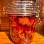 Red chili pickle stored in a glass jar.