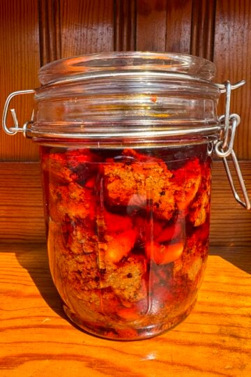 Red chili pickle stored in a glass jar.